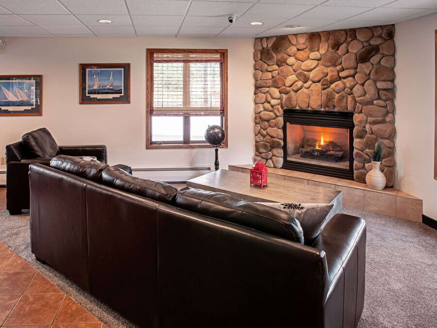 A lobby with a stone fireplace, leather sofa, and framed artwork on the walls.