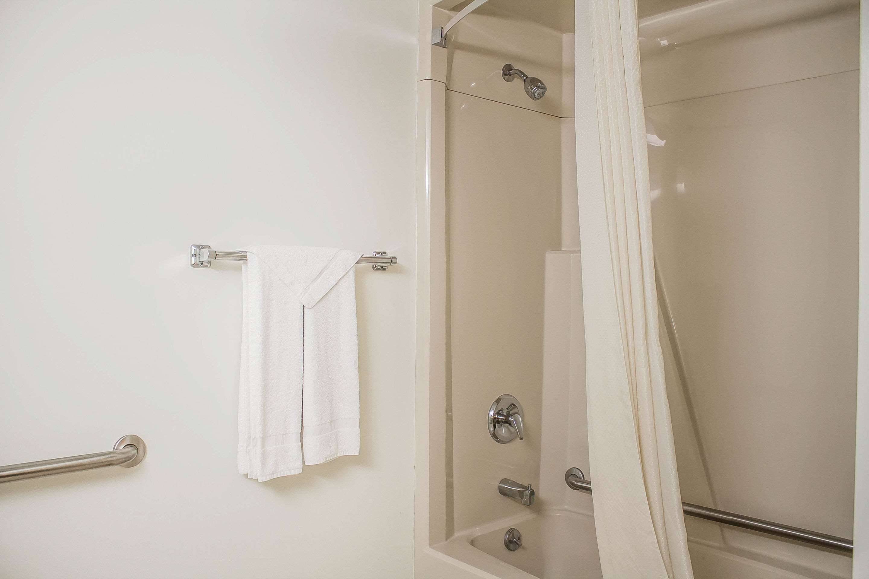 A bathroom with a glass-enclosed shower, a towel rack, and a grab bar.