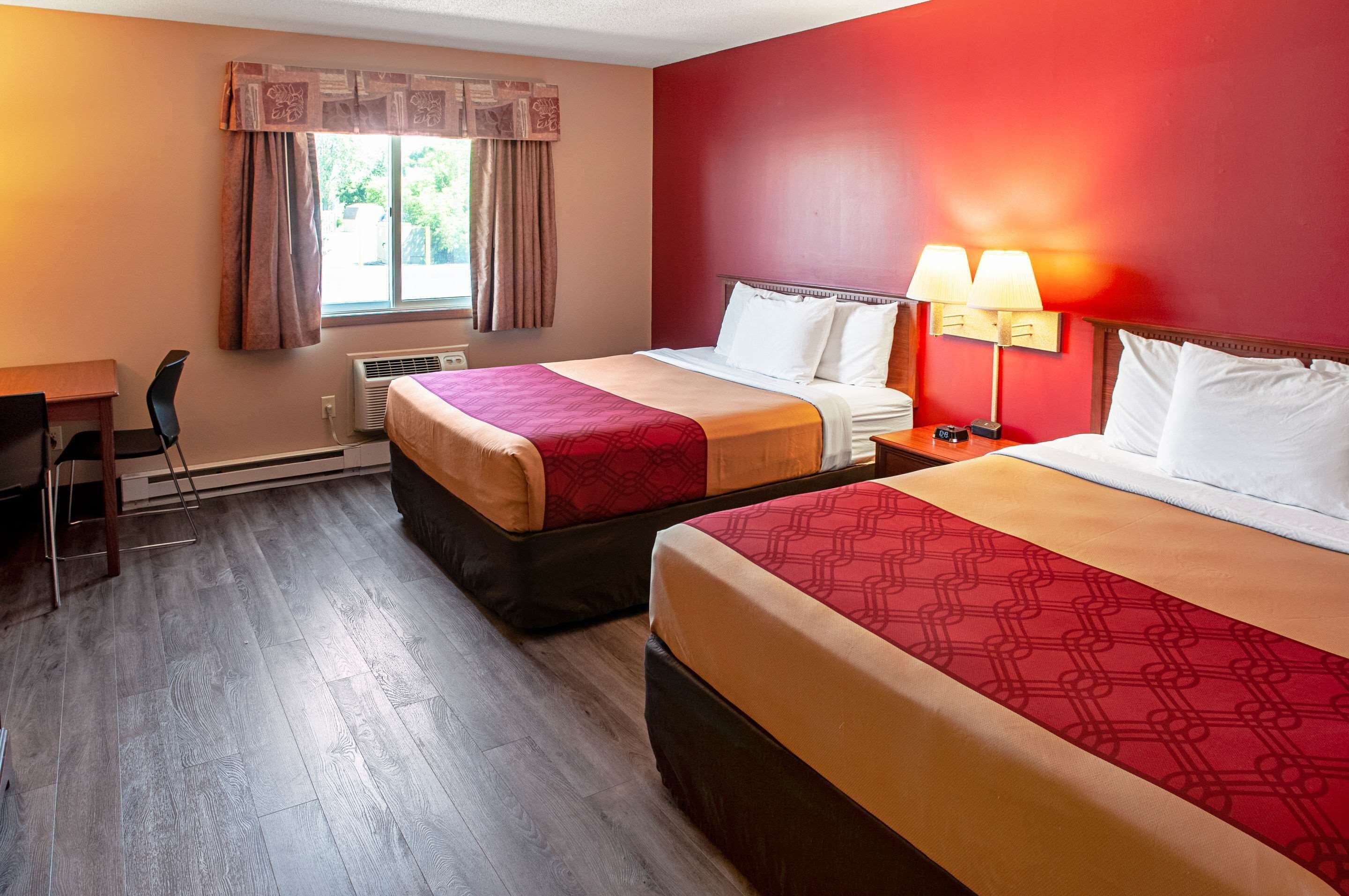 A hotel room with two beds, a desk, and a chair.