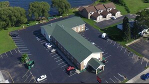 An aerial view of a building with a parking lot, a green roof, and a body of water in the background.