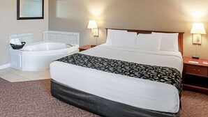A hotel room with a large bed, a separate bathtub, two bedside lamps, and a framed picture on the wall.