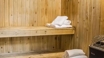 Un sauna con paredes y bancos de madera, y un perchero con toallas dobladas.