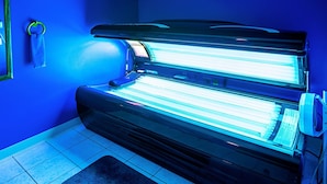 A tanning bed in a room with blue walls and tiled flooring.