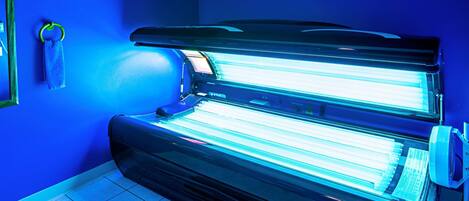 A tanning bed in a room with blue walls and tiled flooring.