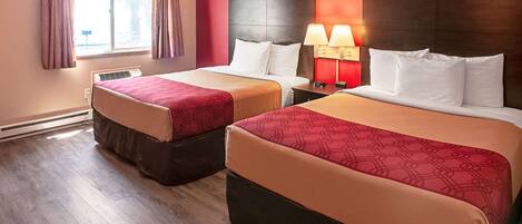 A hotel room with two beds, a window with curtains, a heater, and a nightstand with lamps.