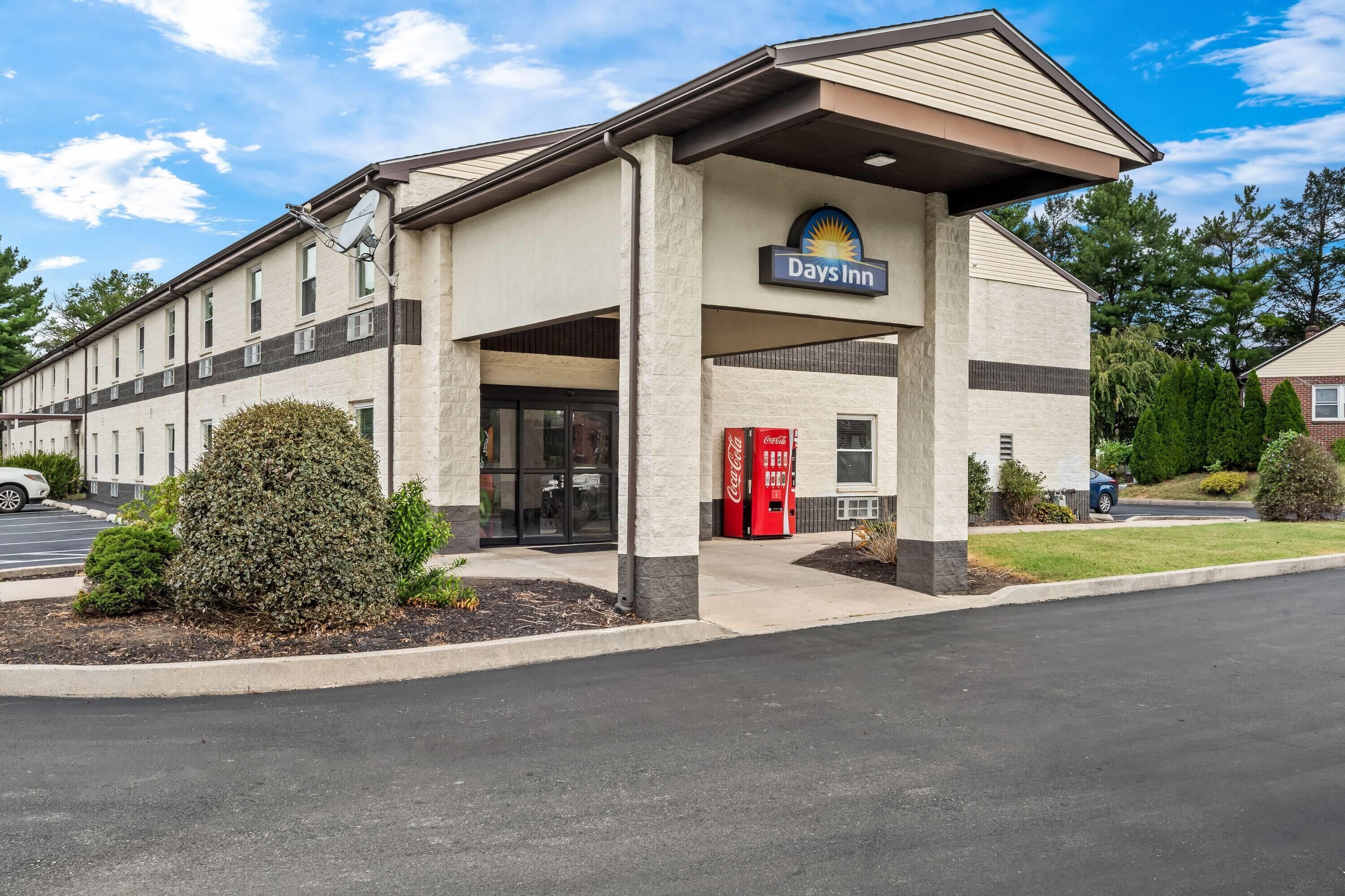 A Days Inn building with a simple facade, a Coca-Cola vending machine, and a red door.