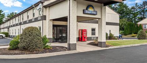 A Days Inn building with a simple facade, a Coca-Cola vending machine, and a red door.