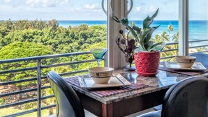 Un espace repas avec vue sur l’océan, une table avec des chaises et une plante en pot.