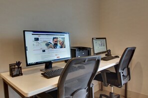 A workspace with two monitors, a keyboard, and office chairs.