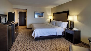 Una habitación de hotel con cama, escritorio con lámpara, televisión y puerta.