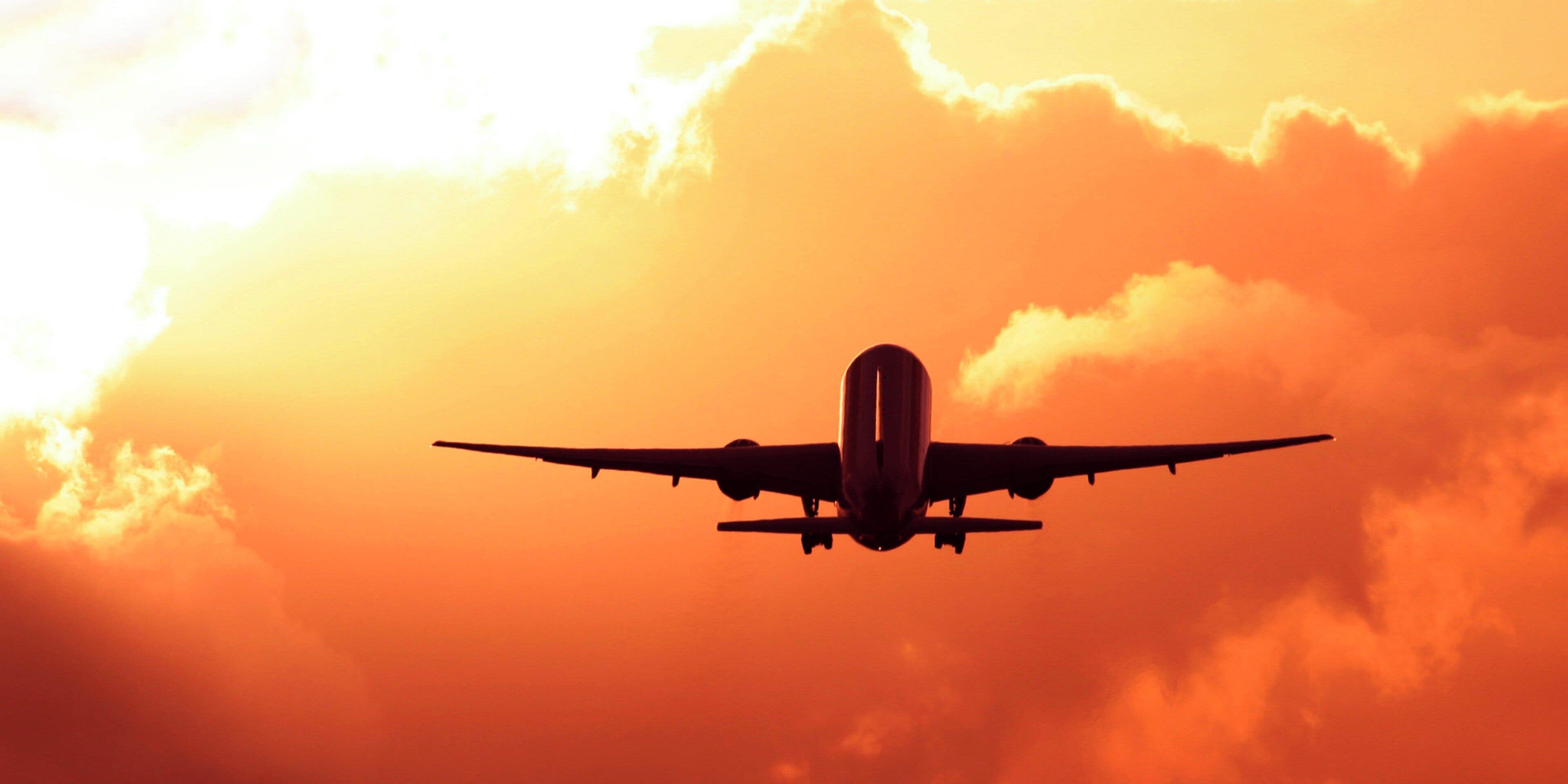 Un avión volando contra un cielo al atardecer.