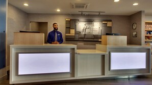 A hotel reception desk with a digital display, a clock, and a sign for Holiday Inn Express.