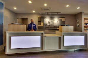 A hotel reception desk with a digital display, a clock, and a sign for Holiday Inn Express.