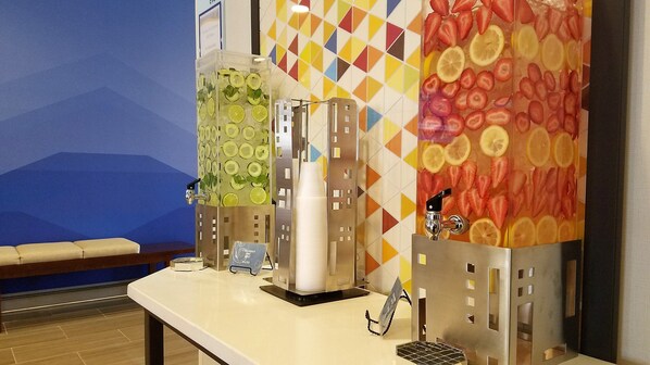 A self-service beverage station with multiple dispensers, including one with a lime and mint flavor, and another with a strawberry and lemon flavor.