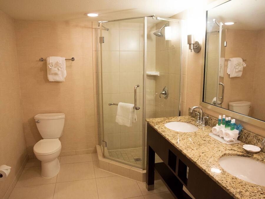 A modern bathroom with a glass-enclosed shower, two sinks, and a toilet.