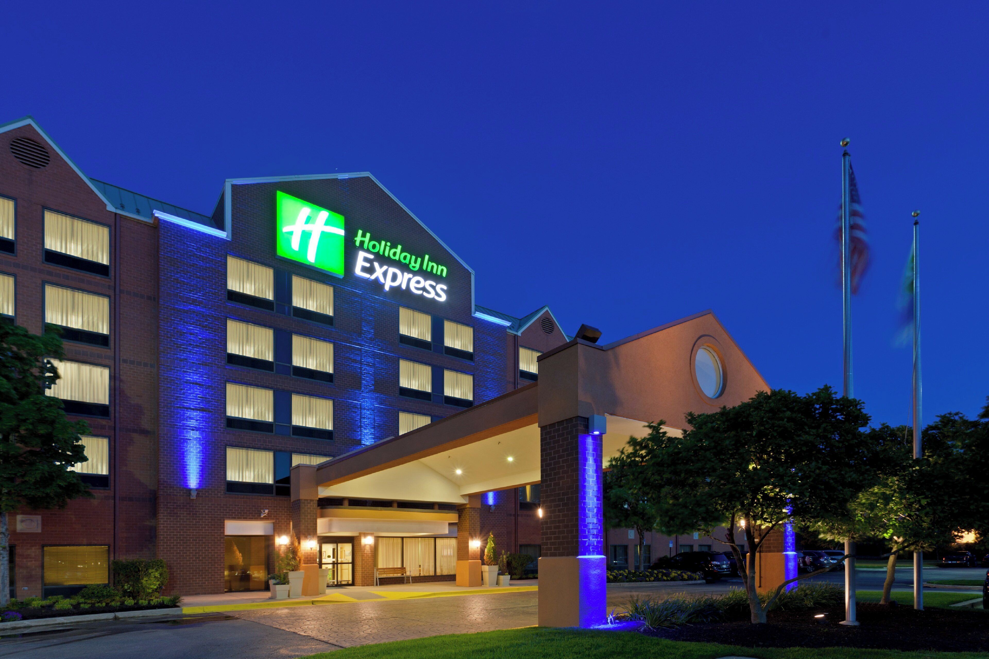 Un hôtel Holiday Inn Express, reconnaissable à son enseigne bien visible, à son entrée abritée et à son mât de drapeau.