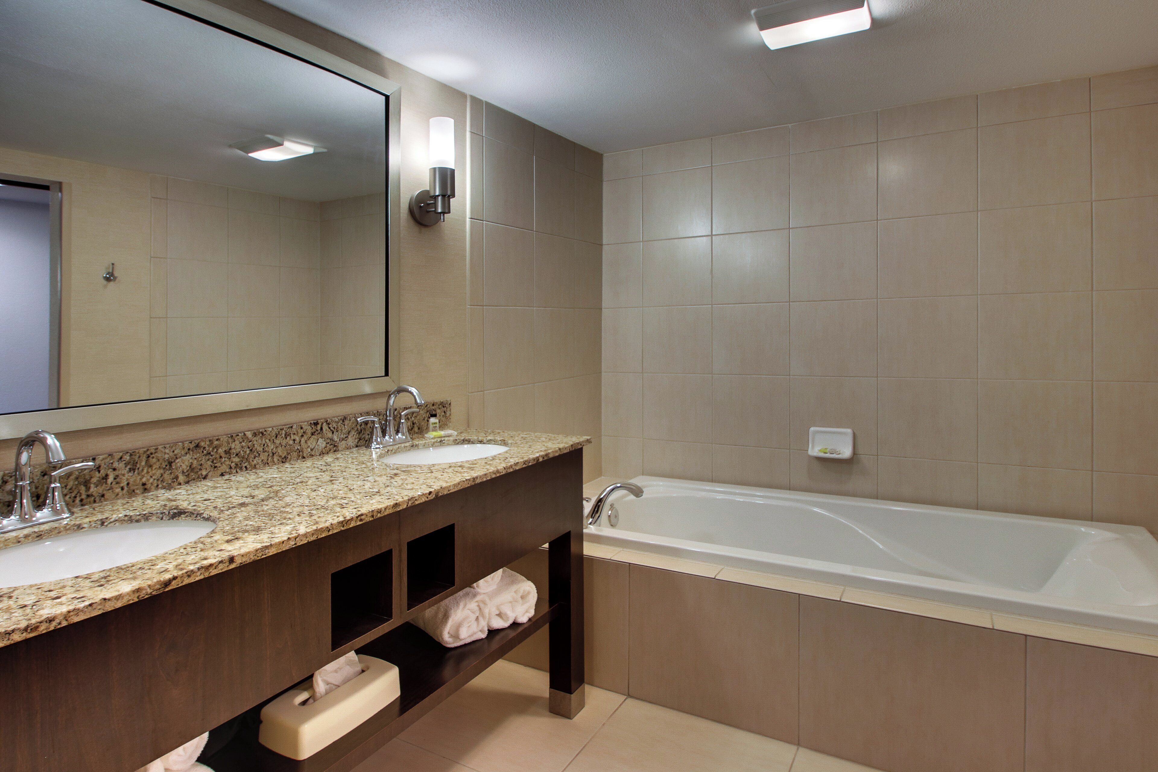 A bathroom with two sinks, a large bathtub, and a mirror above the vanity.