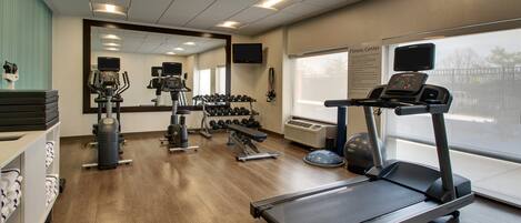 Un gimnasio con cintas de correr, mancuernas y equipamiento de ejercicio.
