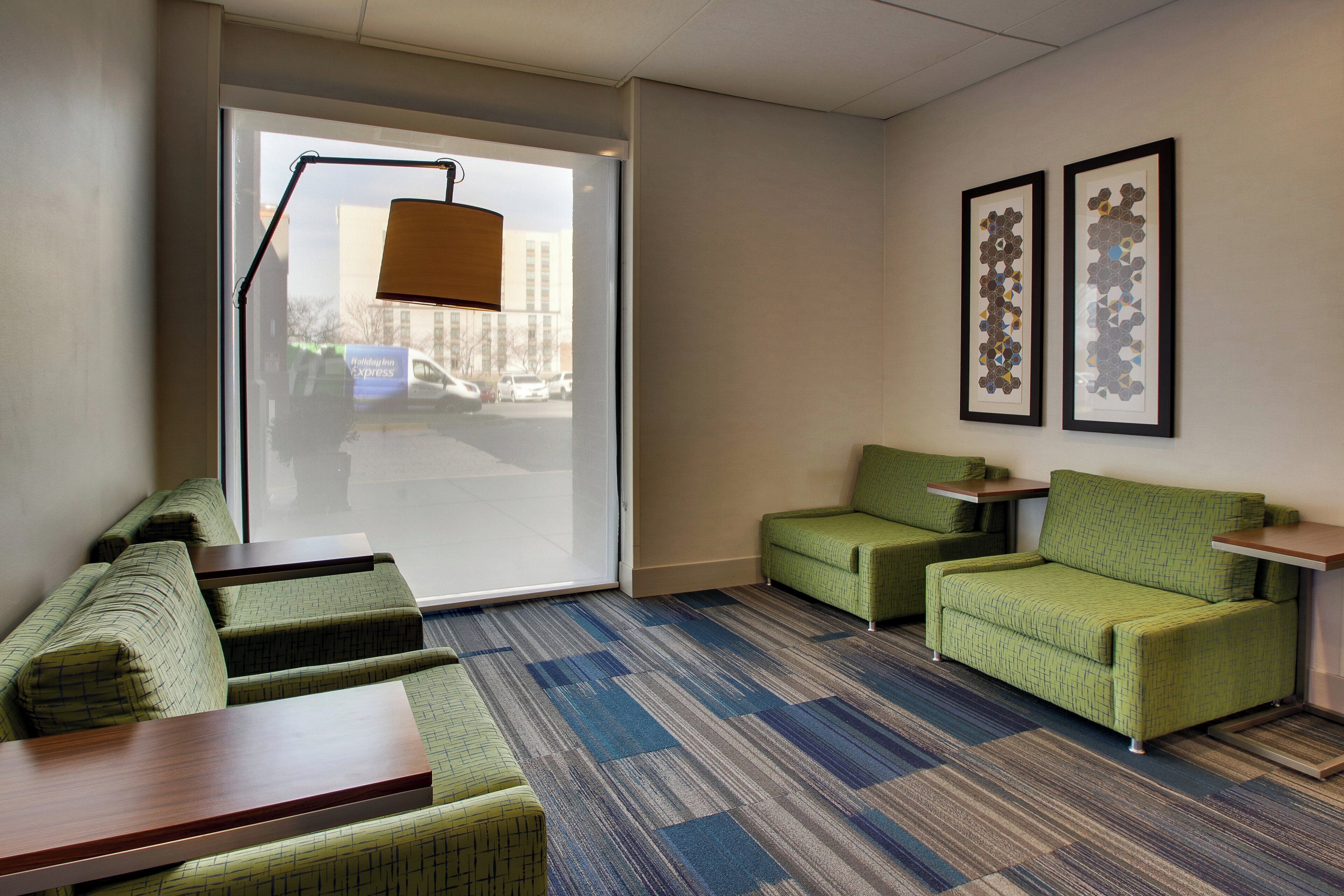 A hotel room with a seating area, a large window, and two framed artworks on the wall.