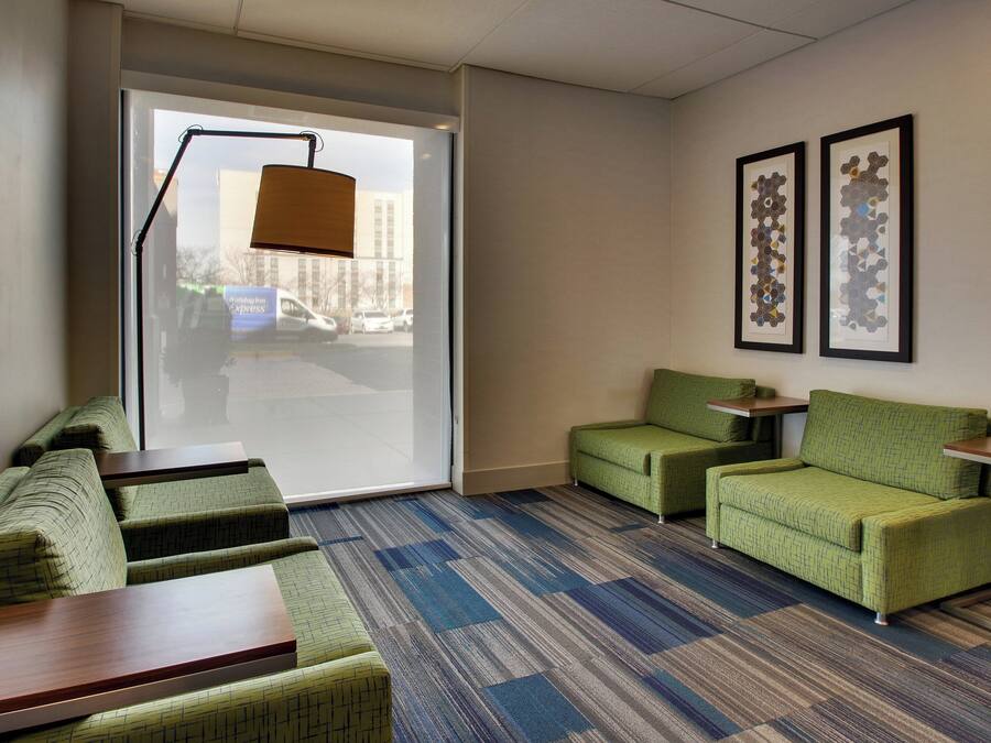 Habitación de hotel con zona de estar, un ventanal grande y dos cuadros en la pared.