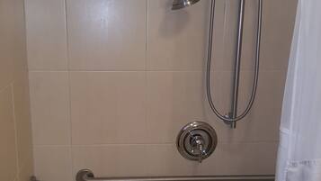 A shower area with a grab bar, a handheld showerhead, and a curtain.