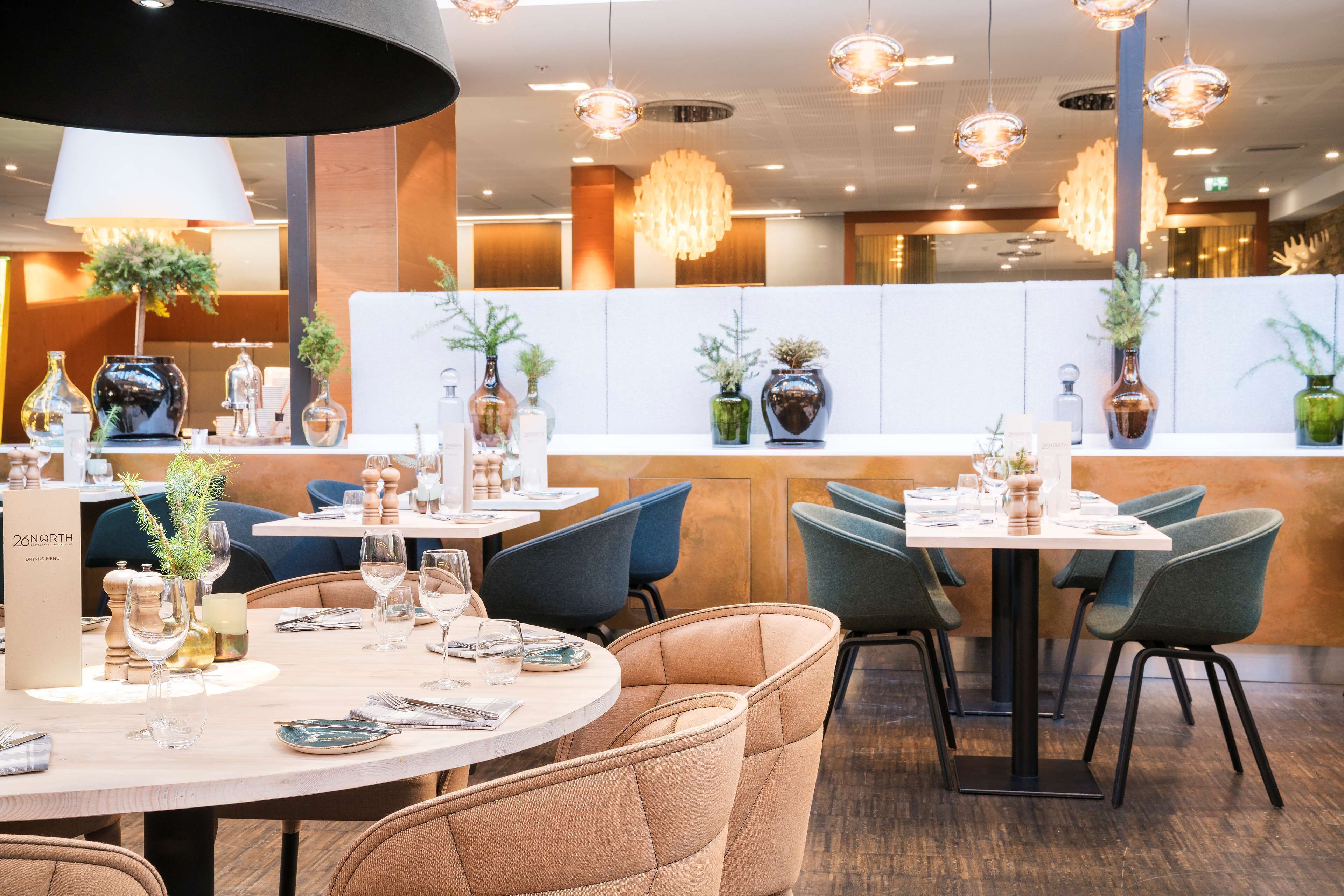 A restaurant with round tables, blue chairs, and a white partition.