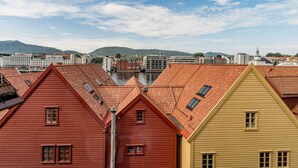 A row of colorful buildings with red and yellow facades, a river in the background, and a clear sky.