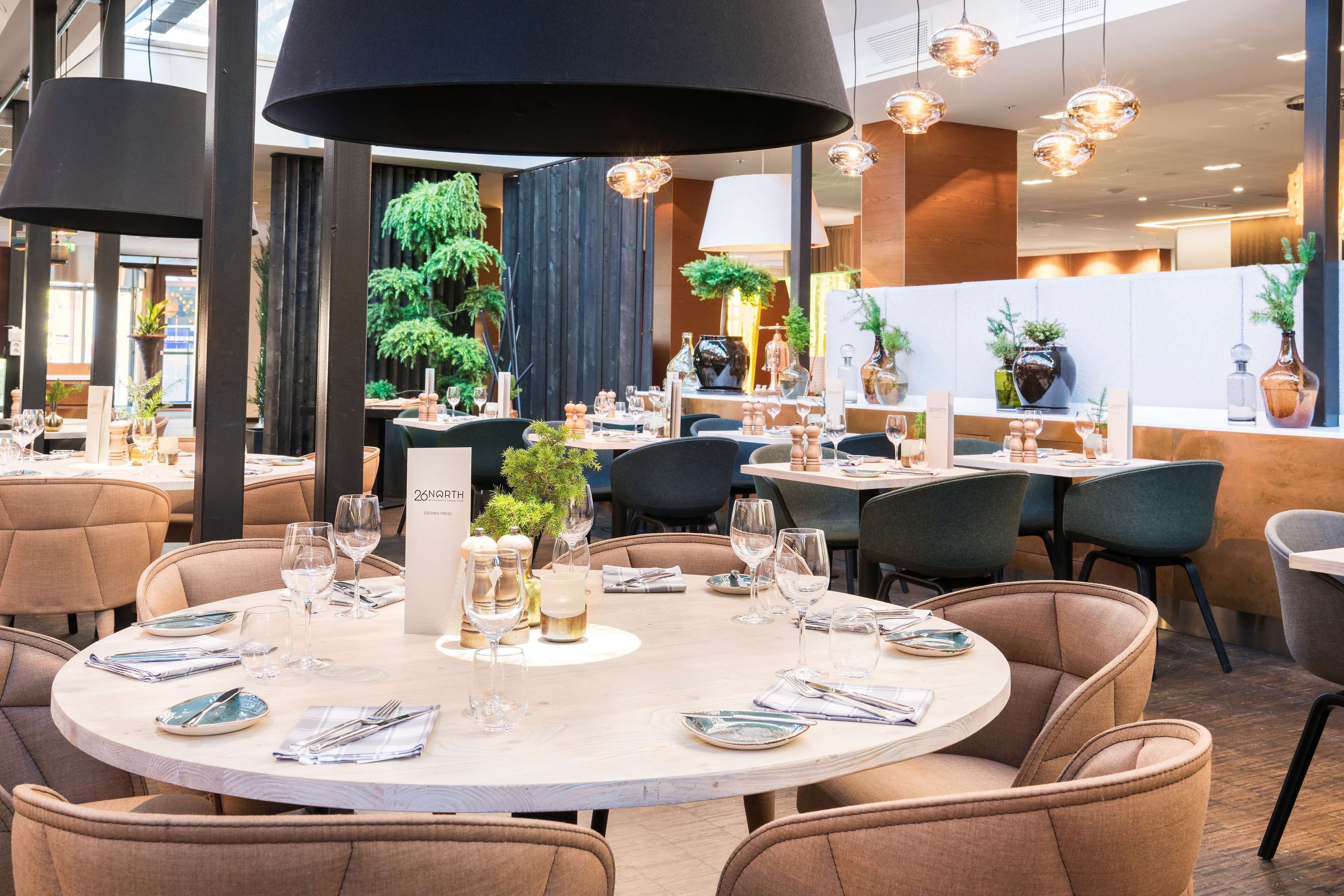 Un restaurante con mesas redondas, sillas e iluminación colgante.