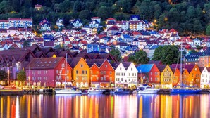 En by ved vandet med farverige bygninger, en havn med både og en kirke på en bakke.