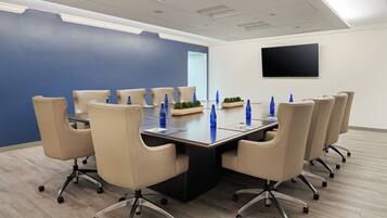 A conference room with a long table, beige chairs, and blue water bottles.