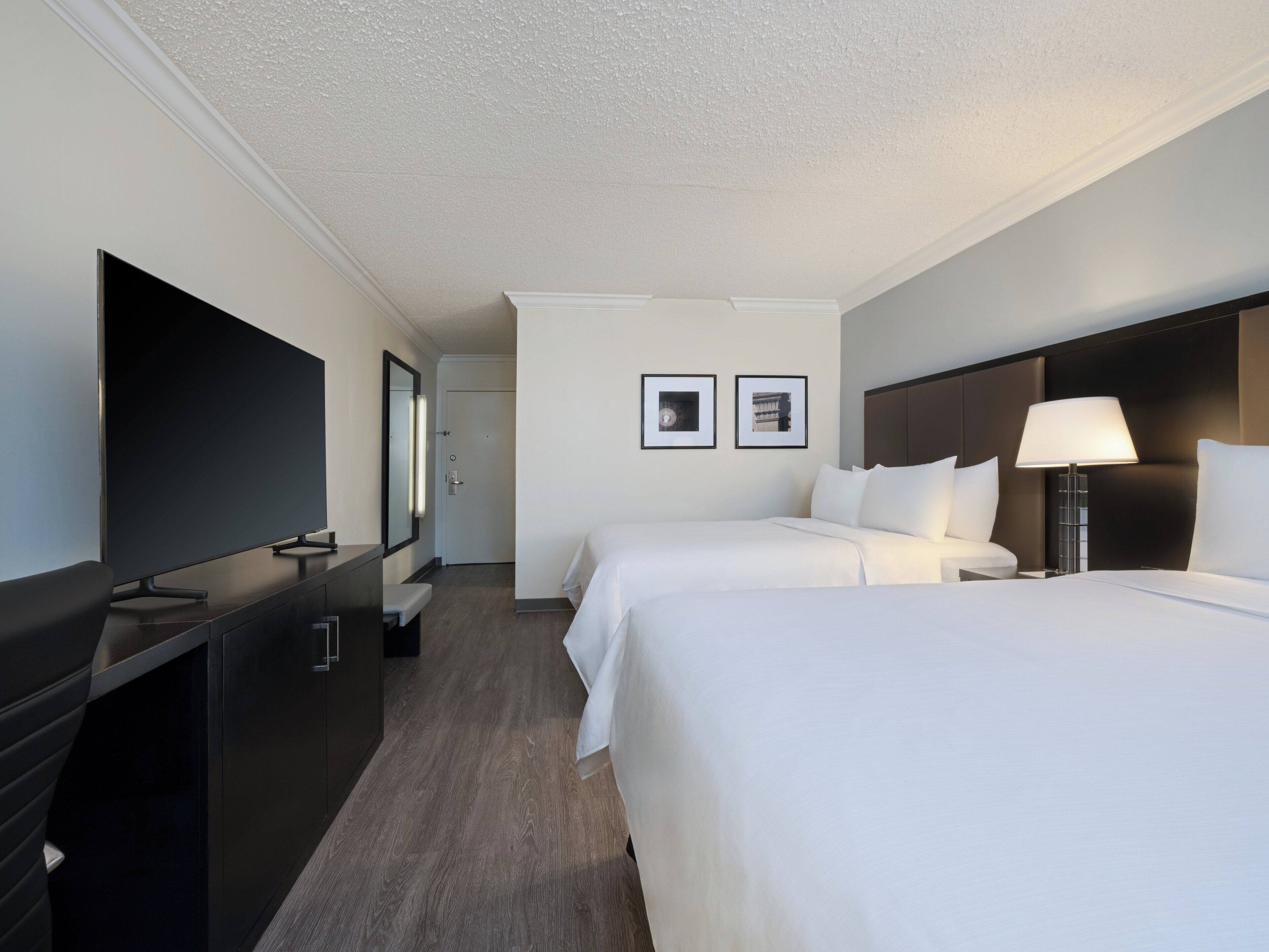 Een hotelkamer met twee bedden, een televisie, een bureau en een nachtkastje met een lamp.