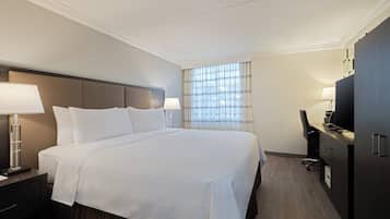 A hotel room with a large bed, bedside tables with lamps, a desk with a chair, and a television.