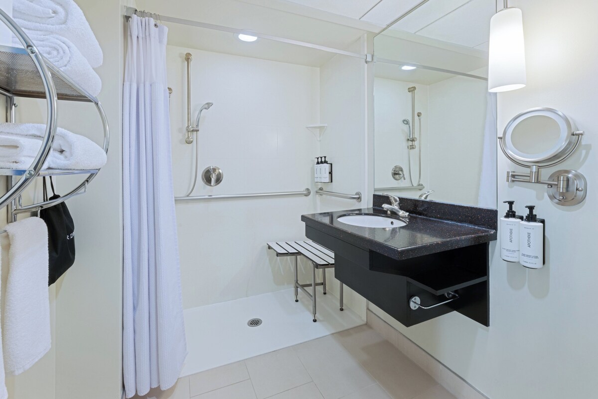 A modern bathroom with a shower, a sink, and a mirror.