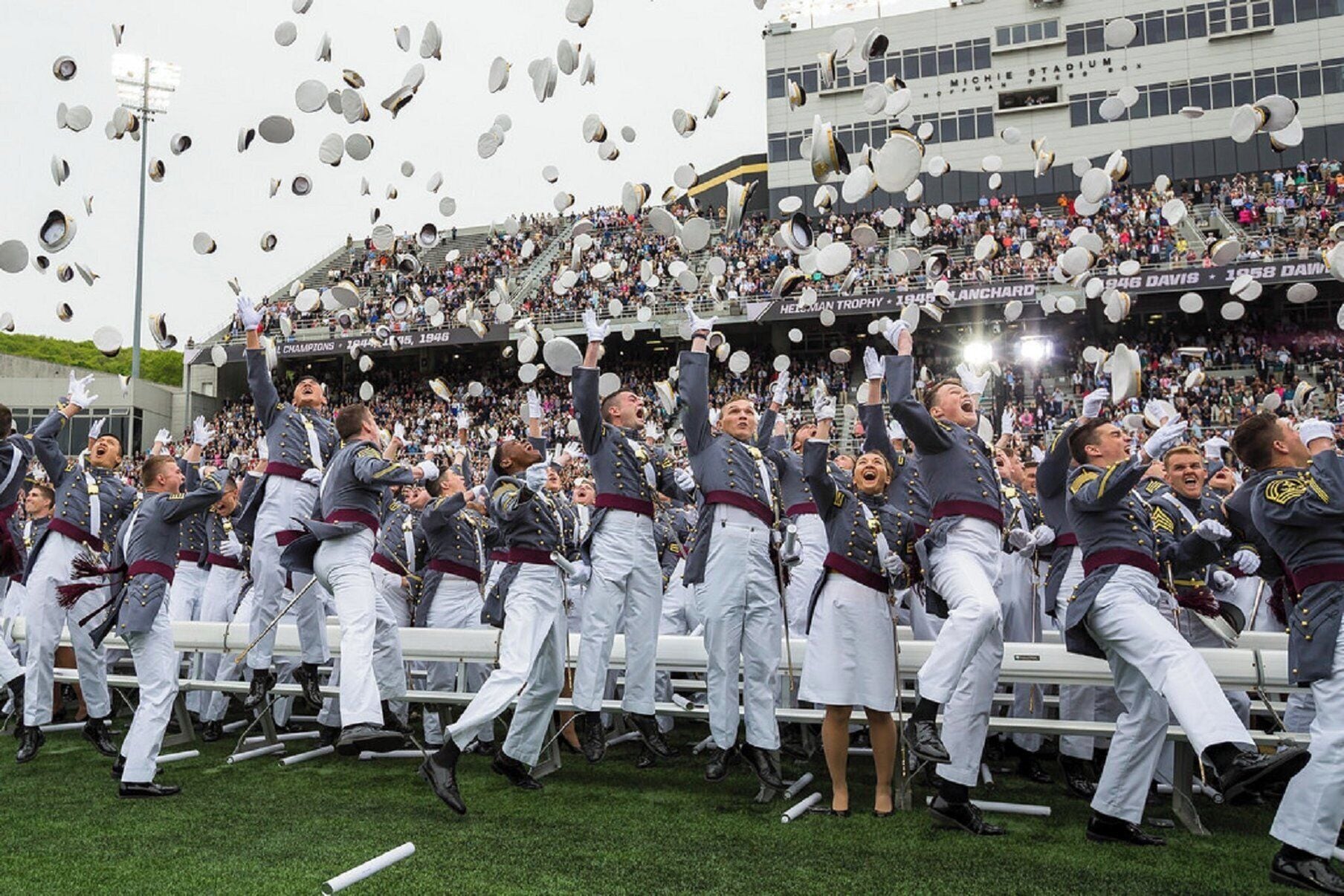 A group of people in uniform celebrating with caps being thrown in the air.