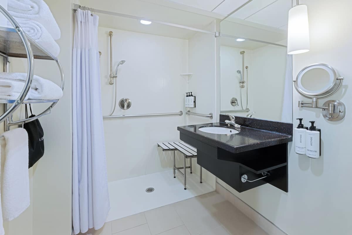 A modern bathroom with a shower, a sink, a mirror, and a towel rack.