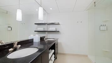 Een moderne badkamer met twee wastafels, een grote spiegel en een douchecabine met glazen wanden.