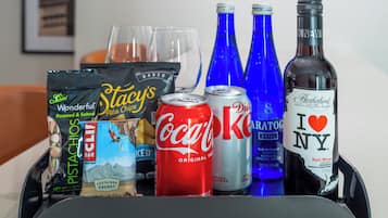 A tray with snacks, drinks, and a bottle of wine.