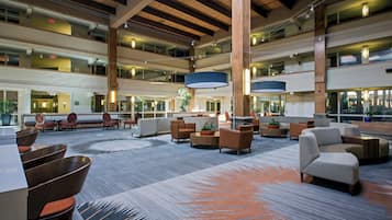 A spacious lobby with multiple seating areas, a high ceiling with wooden beams, and a patterned carpet.