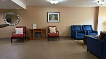 Un vestíbulo amplio con una consola de madera, dos sillones rojos y un sofá azul.