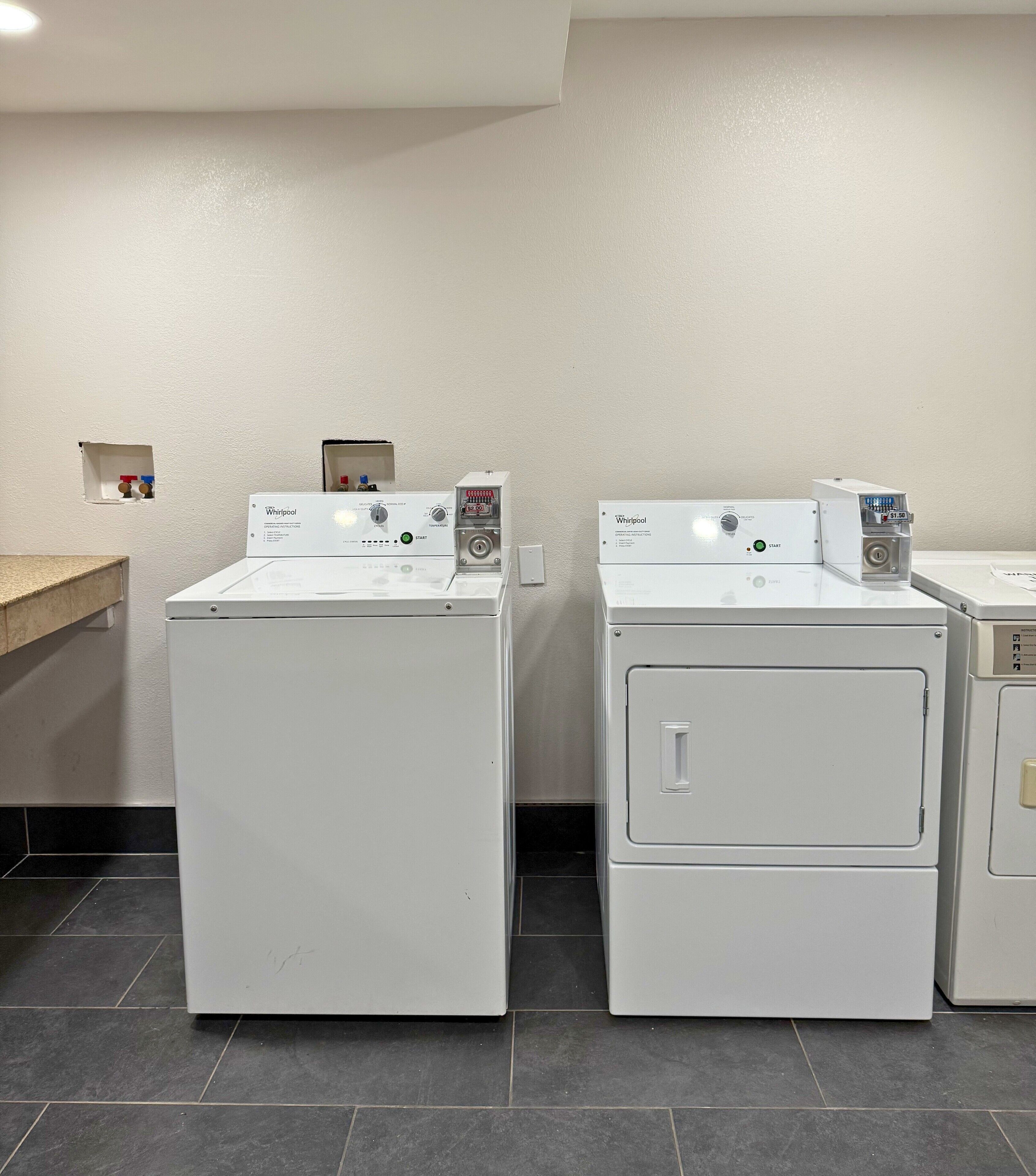Dos lavadoras Whirlpool de carga frontal en un lavadero con piso de baldosas y pared blanca.