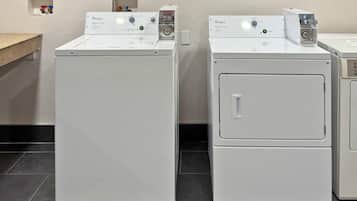 Two front-loading Whirlpool washers in a laundry room with a countertop and a small shelf with bottles.