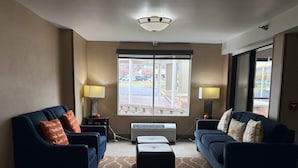 Une chambre d’hôtel avec deux canapés, une table basse, une lampe et une grande fenêtre.