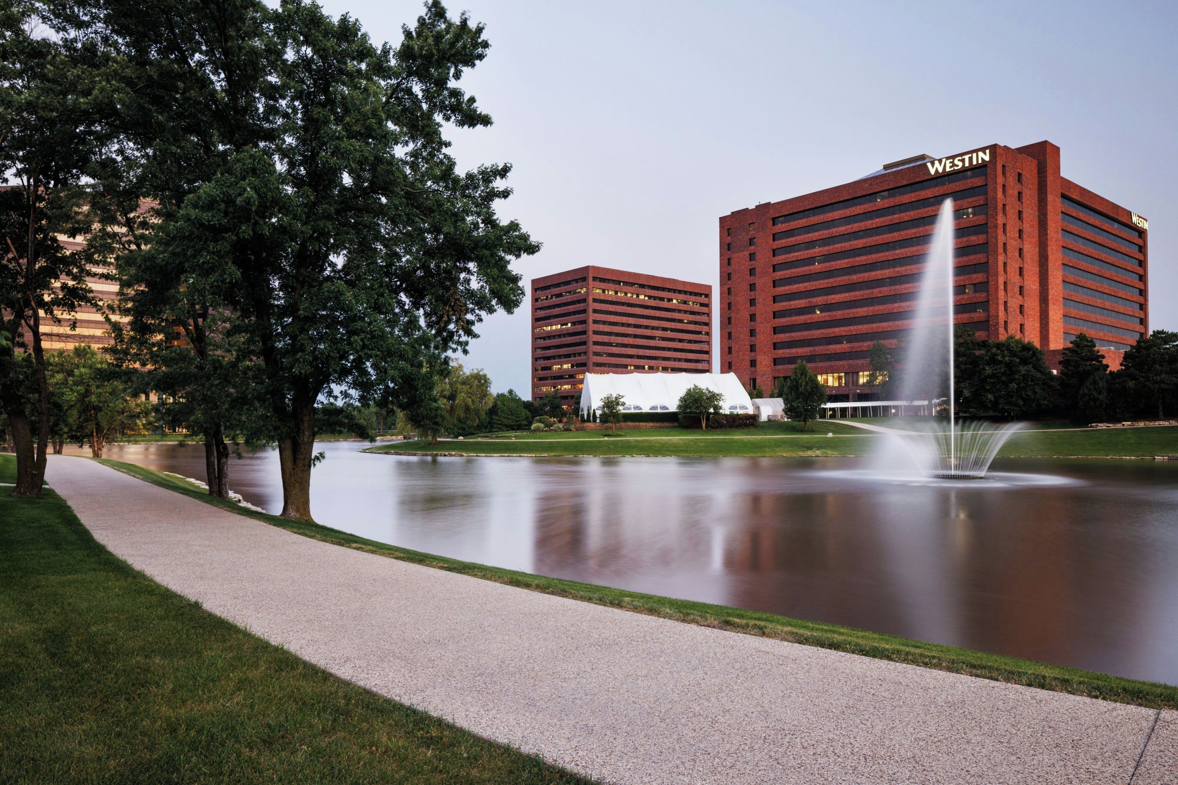 A hotel with a large building and a fountain in the foreground.