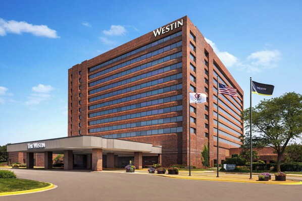Un hotel Westin con fachada de ladrillo moderno, un acceso cubierto y una bandera estadounidense.