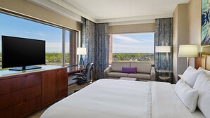 A hotel room with a large bed, a desk with a TV, a sofa, and a view of the city. - The Westin Chicago Northwest (Itasca)