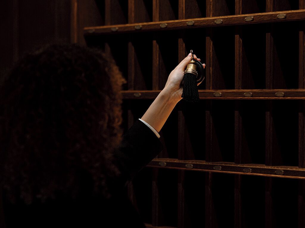 A person holding a key near a wooden door with a metal handle.