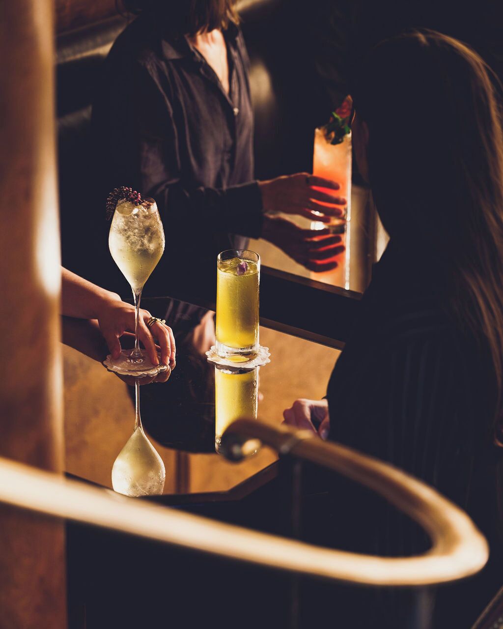 A bar area with a person pouring a drink into a tall glass.