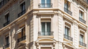 Een meerhoog gebouw met een klassieke architectuur, herkenbaar aan de gebogen deuropeningen en decoratieve ijzeren balkons.