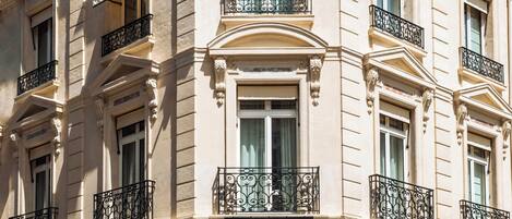 A multi-story building with a classic architectural style, featuring arched doorways and decorative iron railings.