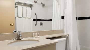 A bathroom with a sink, mirror, towel rack, shower, and toilet.